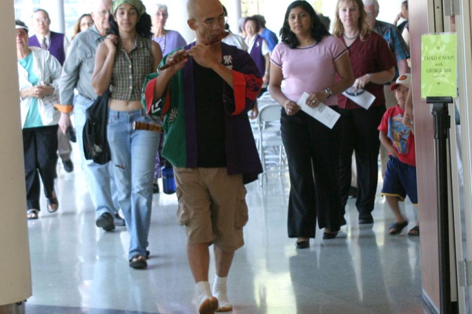 George Abe of Kinnara Taiko plays a wind instrument and leads a group of observers